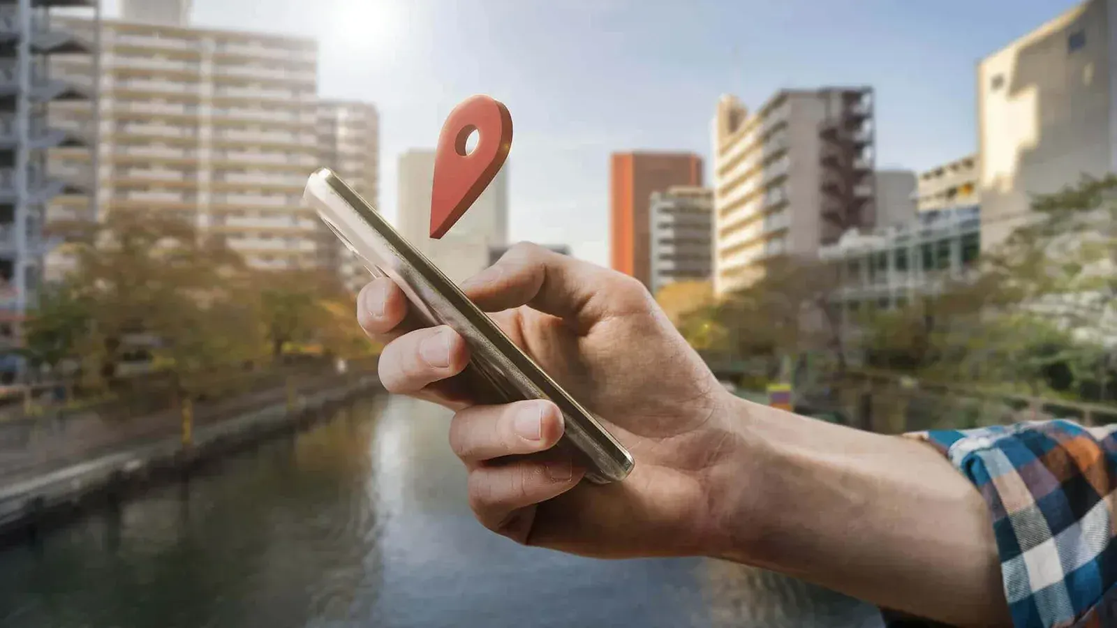 A person holds a smartphone displaying location services while a map pin icon hovers above the screen, representing local SEO, Google Maps visibility, location based search results, and mobile business discovery in an urban setting.